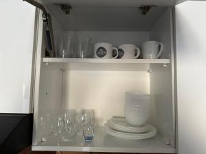 un placard avec des assiettes, des verres et un vase dans l'établissement ATRIUM Mountain View Apartment, New Gudauri, à Goudaouri
