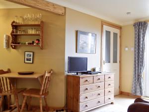 a living room with a table and a television on a dresser at Waterside Lodge in Port Appin