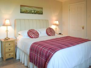 een slaapkamer met een bed met rode en witte kussens bij Carthouse Cottage in Carew