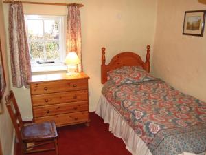 a bedroom with a bed and a dresser and a window at Lobstone Cottage in Rosthwaite