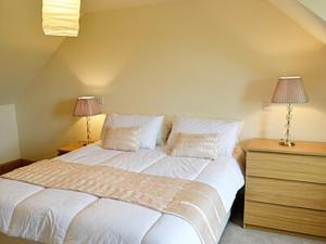 a bedroom with a large white bed and two lamps at Tara Cottage in Gordon