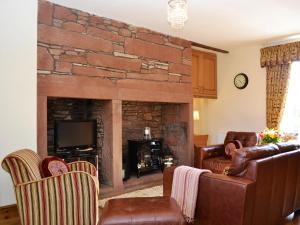 a living room with couches and a stone fireplace at The Old Dairy in Crosscanonby