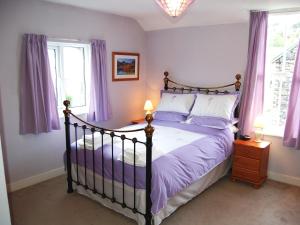 1 Schlafzimmer mit einem Bett mit lila Laken und Fenstern in der Unterkunft Beech End in Braithwaite