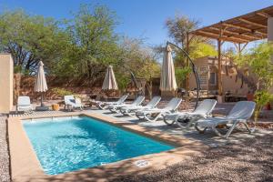 a swimming pool with lounge chairs and umbrellas at Casa Solcor Boutique Bed & Breakfast in San Pedro de Atacama