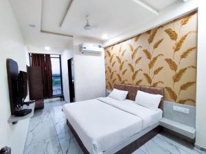 RājpīplaにあるHotel Shivamのベッドとテレビ付きのホテルルーム