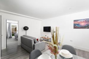 Skyvillion - London Enfield Chase Apartments with Parking & Wifi في انفيلد: غرفة معيشة بيضاء مع أريكة وطاولة