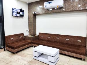RājpīplaにあるHotel Shivamの茶色のソファとテレビが備わる待合室