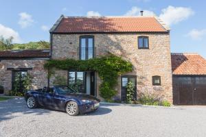 a blue car parked in front of a brick house at Hayloft in Cheddar