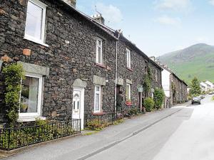 a brick building on a street next to a road at Stybarrow View Cottage in Glenridding