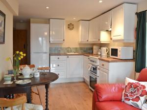 a kitchen with white cabinets and a red couch and a table at Ty Newydd Cottage in Hoel-galed
