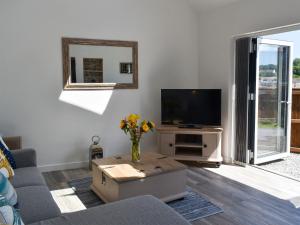 una sala de estar con TV y un jarrón de flores en Apple Barn Cottage, en Brixham