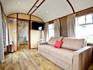 sala de estar con sofá y algunas ventanas en Brunel Boutique Railway Carriage 4, en Dawlish Warren