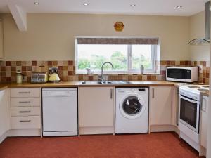 a kitchen with a washing machine and a sink at Magnolia in Chickerell