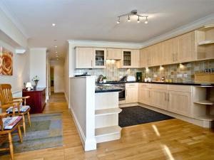 uma cozinha com armários de madeira e uma sala de jantar em 1 Roundham Heights em Paignton