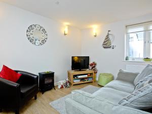 een woonkamer met een bank en een tv bij Little Gem in Weymouth