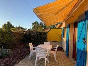 stół i krzesła na patio z żółtym parasolem w obiekcie MAISON LANDES OCEAN w mieście Saint-Julien-en-Born