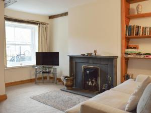 a living room with a fireplace and a tv at Bridge House in Threlkeld