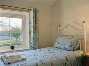 a bedroom with a bed with a window and towels at Bridge House in Threlkeld