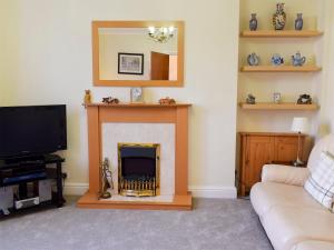 sala de estar con chimenea y TV en Alexandra Cottage, en Windermere
