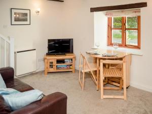 a living room with a table and a tv and a table and chairs at Lilac Cottage Dunstan in Craster