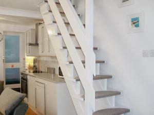 a white spiral staircase in a kitchen with a counter at Salty Cottage in Newlyn