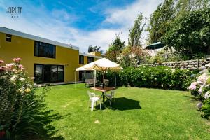 ein Garten mit Sonnenschirm, Tisch und Stühlen in der Unterkunft Hotel La Gruta in Arequipa