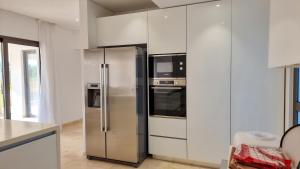 a stainless steel refrigerator in a kitchen with white cabinets at Leto 13 Villa in Paphos City