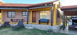 una pequeña casa amarilla con sillas y mesa en Portal del Uritorco en Capilla del Monte