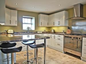 a kitchen with white cabinets and a large island with bar stools at The Granary - 26502 in High Etherley