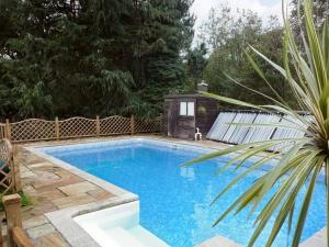 una piscina en un patio trasero con una valla de madera en Pats Cottage en Dore