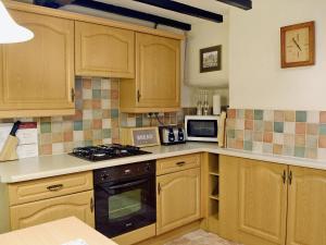 a kitchen with wooden cabinets and a stove top oven at Pats Cottage in Dore