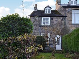 an old brick house with a window and bushes at Pats Cottage in Dore