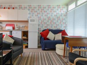 a living room with a blue couch and a kitchen at Poppy in Cromer