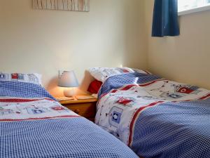two twin beds in a bedroom with a lamp at Poppy in Cromer
