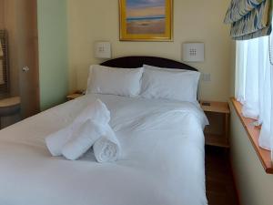a white bed with two folded towels on it at Trellee in Budock Water
