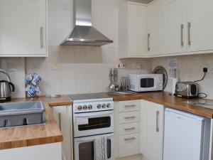 een keuken met witte kasten en een fornuis met oven bij Sea Breeze in Hopton on Sea