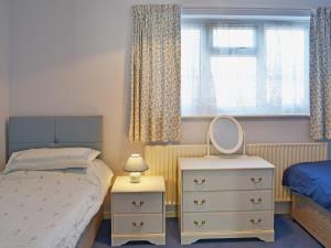 een slaapkamer met een bed, een spiegel en een dressoir bij Sea Breeze in Hopton on Sea