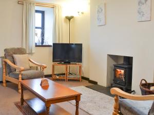 a living room with a tv and a fireplace at The Gatehouse in Aberffraw