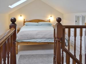 a bedroom with a wooden bed and a staircase at The Gatehouse in Aberffraw