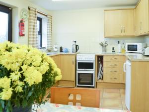 a kitchen with wooden cabinets and a white oven at The Gatehouse in Aberffraw