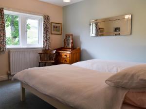 a bedroom with two beds and a mirror and a window at Fell View in Kettlewell