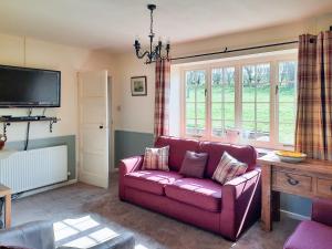 a living room with a purple couch and a tv at Moorhouse Farm Cottage in Hovingham