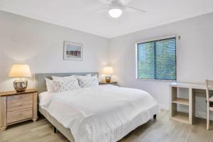 a white bedroom with a large bed and a window at Paralia Condo in Clearwater Beach