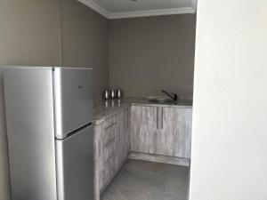 a kitchen with a white refrigerator and wooden cabinets at Mourice Lodge in Sterkspruit