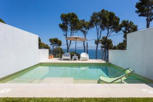 卡萊利亞德帕拉弗魯赫爾的住宿－Luxury Villa in front of the sea PROA，一个带两把椅子和遮阳伞的游泳池