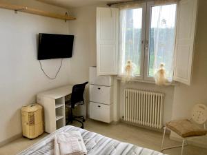 een slaapkamer met een bed, een bureau en een televisie bij Appartamenti Pesaro Mare Ledimar in Pesaro