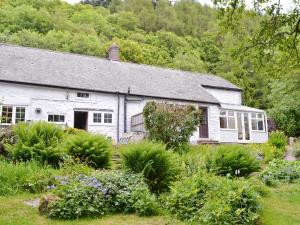 a white house with a garden in front of it at The Old Smithy in Llanbadarn-fynydd