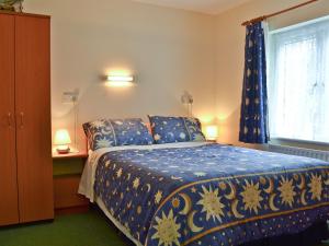 a bedroom with a blue and gold bed with a window at Blackbird Cottage in Llanfair Caereinion