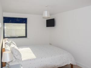 a white bedroom with a bed and a window at Sea Drift in West Bay