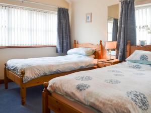 a bedroom with two beds and two windows at Hen Stabl - 16983 in Brynsiencyn